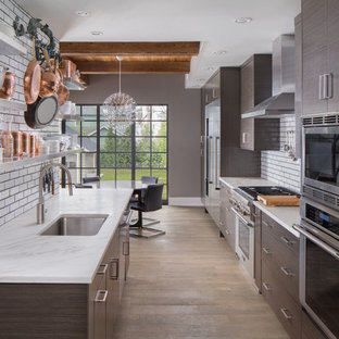 Mid-sized trendy galley eat-in kitchen photo in Other with flat-panel cabinets, brown cabinets, subway tile backsplash, stainless steel appliances, an island and an undermount sink