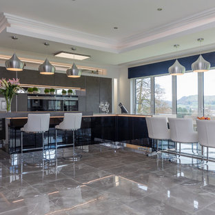 This is an example of a contemporary single-wall kitchen in Other with flat-panel cabinets, black cabinets, black appliances, an island, grey floors and grey worktops.