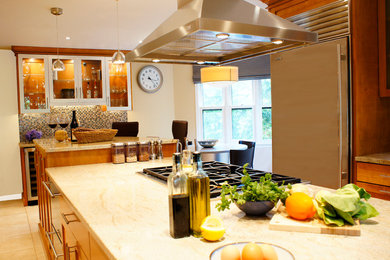 ニューヨークにあるトランジショナルスタイルのおしゃれなアイランドキッチン (シェーカースタイル扉のキャビネット、中間色木目調キャビネット、マルチカラーのキッチンパネル、モザイクタイルのキッチンパネル、シルバーの調理設備) の写真
