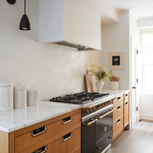 Design ideas for a small contemporary single-wall open plan kitchen in Columbus with an undermount sink, louvered cabinets, medium wood cabinets, marble benchtops, white splashback, stainless steel appliances, light hardwood floors, grey floor and white benchtop.