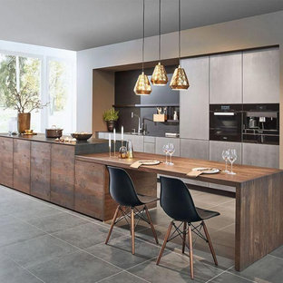 Example of a large trendy single-wall ceramic tile and gray floor open concept kitchen design in Columbus with an undermount sink, flat-panel cabinets, gray cabinets, gray backsplash, gray countertops, quartzite countertops, stone slab backsplash, black appliances and an island