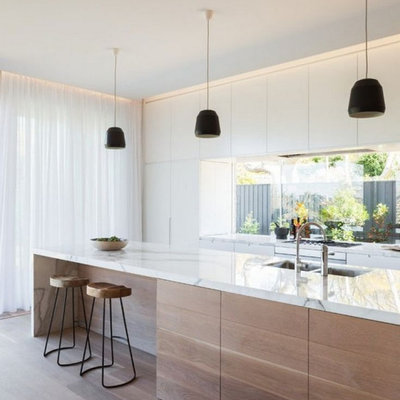 Example of a large trendy galley light wood floor and brown floor open concept kitchen design in Columbus with an undermount sink, flat-panel cabinets, light wood cabinets, marble countertops, stainless steel appliances, an island and white countertops
