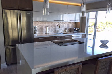 Photo of a medium sized contemporary single-wall kitchen in Detroit with a submerged sink, flat-panel cabinets, engineered stone countertops, white splashback, ceramic splashback, stainless steel appliances, porcelain flooring and an island.