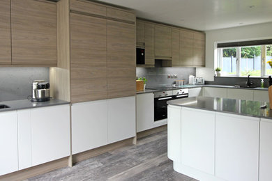 Design ideas for a medium sized contemporary l-shaped open plan kitchen in West Midlands with a double-bowl sink, flat-panel cabinets, white cabinets, quartz worktops, grey splashback, black appliances, laminate floors, an island, brown floors and grey worktops.