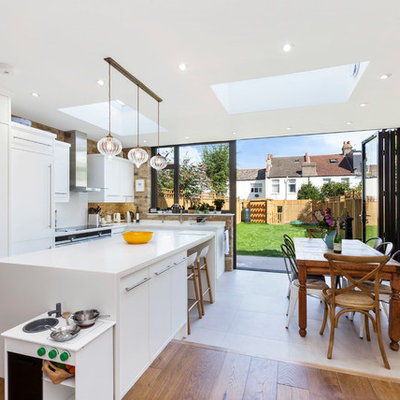 Mid-sized trendy single-wall cement tile floor and gray floor open concept kitchen photo in London with flat-panel cabinets, white cabinets, quartzite countertops and an island