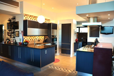 Inspiration for a large contemporary kitchen in Denver with a double-bowl sink, flat-panel cabinets, stainless steel cabinets, engineered stone countertops, multi-coloured splashback, mosaic tiled splashback, integrated appliances and porcelain flooring.