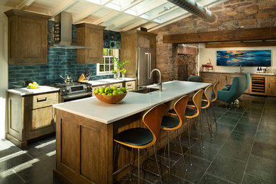 Cette image montre une grande cuisine parallèle rustique en bois brun avec un évier encastré, un placard à porte shaker, une crédence bleue, un électroménager en acier inoxydable, îlot, un sol gris, un plan de travail blanc et une crédence en céramique.