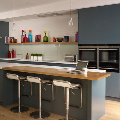 Kitchen - contemporary light wood floor kitchen idea in London with flat-panel cabinets, blue cabinets, white backsplash, stainless steel appliances and an island