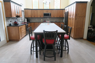 Eat-in kitchen - large contemporary u-shaped porcelain tile eat-in kitchen idea in Providence with a double-bowl sink, recessed-panel cabinets, medium tone wood cabinets, quartz countertops, gray backsplash, mosaic tile backsplash, black appliances and an island