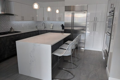 Large trendy porcelain tile and gray floor kitchen pantry photo in New York with an undermount sink, flat-panel cabinets, white cabinets, quartz countertops, white backsplash, marble backsplash, stainless steel appliances, an island and white countertops