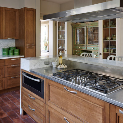 Example of a trendy kitchen design in Seattle with stainless steel appliances, stainless steel countertops, recessed-panel cabinets, medium tone wood cabinets, white backsplash and stone slab backsplash