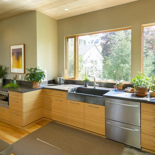 Photo of a large contemporary open plan kitchen in Boston with a farmhouse sink, flat-panel cabinets, beige cabinets, concrete benchtops, stainless steel appliances, bamboo floors and with island.