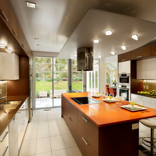 Inspiration for a large contemporary galley eat-in kitchen in Philadelphia with a double-bowl sink, flat-panel cabinets, white cabinets, quartz benchtops, beige splashback, glass tile splashback, stainless steel appliances, porcelain floors, with island and orange benchtop.