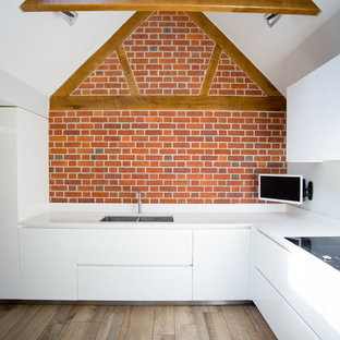 Design ideas for a large contemporary u-shaped open plan kitchen in London with an integrated sink, flat-panel cabinets, white cabinets, solid surface benchtops, white splashback, stone slab splashback, stainless steel appliances, porcelain floors and a peninsula.