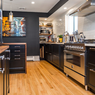 Foto di una cucina design chiusa e di medie dimensioni con lavello sottopiano, ante con riquadro incassato, ante nere, top in legno, paraspruzzi bianco, elettrodomestici in acciaio inossidabile, top marrone, paraspruzzi con piastrelle diamantate, parquet chiaro e pavimento beige