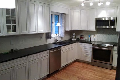 Example of a large trendy u-shaped light wood floor eat-in kitchen design in Providence with an undermount sink, beaded inset cabinets, white cabinets, white backsplash, ceramic backsplash and stainless steel appliances