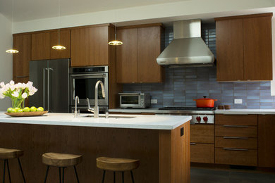 他の地域にあるコンテンポラリースタイルのおしゃれなアイランドキッチン (フラットパネル扉のキャビネット、中間色木目調キャビネット、シルバーの調理設備、スレートの床) の写真