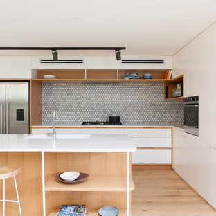 Design ideas for a contemporary kitchen in Sydney with an integrated sink, flat-panel cabinets, white cabinets, blue splashback, mosaic tile splashback, stainless steel appliances, light hardwood floors, with island, beige floor and white benchtop.