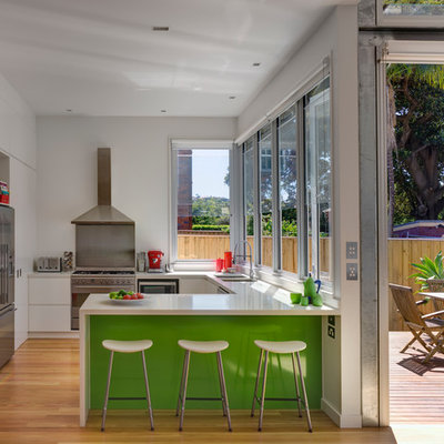 Open concept kitchen - contemporary u-shaped medium tone wood floor open concept kitchen idea in Sydney with a double-bowl sink, flat-panel cabinets, white cabinets, stainless steel appliances and a peninsula