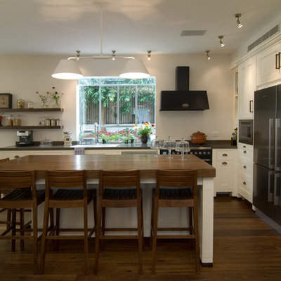 Trendy l-shaped kitchen photo in Tel Aviv with stainless steel appliances, wood countertops, recessed-panel cabinets and white cabinets