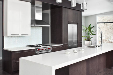 Ejemplo de cocina actual con armarios con paneles lisos, electrodomésticos de acero inoxidable y una isla