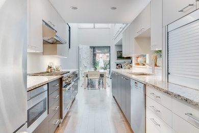 Zweizeilige, Mittelgroße Moderne Wohnküche mit Unterbauwaschbecken, flächenbündigen Schrankfronten, Küchengeräten aus Edelstahl und hellem Holzboden in Chicago