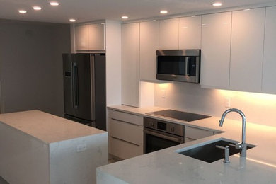 Photo of a medium sized contemporary l-shaped kitchen/diner in Miami with a submerged sink, white cabinets and an island.