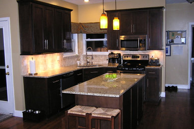 Mid-sized transitional u-shaped medium tone wood floor and brown floor eat-in kitchen photo in Kansas City with an undermount sink, shaker cabinets, granite countertops, dark wood cabinets, beige backsplash, ceramic backsplash, stainless steel appliances and an island