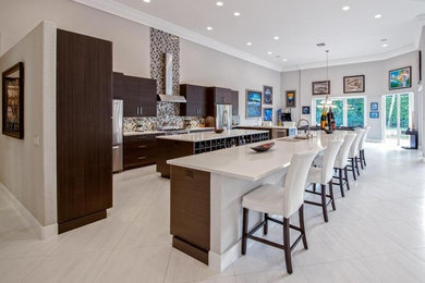 Photo of an expansive contemporary u-shaped kitchen/diner in Miami with flat-panel cabinets, dark wood cabinets, engineered stone countertops, multi-coloured splashback, multiple islands, a submerged sink and stainless steel appliances.