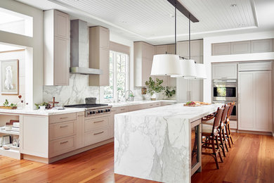 Inspiration for a large timeless l-shaped medium tone wood floor and orange floor kitchen remodel in Denver with recessed-panel cabinets, marble countertops, white backsplash, marble backsplash, stainless steel appliances, an island and beige cabinets