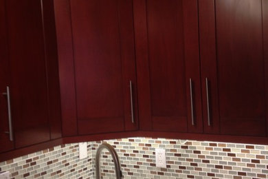 Example of a mid-sized trendy l-shaped dark wood floor eat-in kitchen design in New York with an undermount sink, raised-panel cabinets, white cabinets, marble countertops, gray backsplash, ceramic backsplash, stainless steel appliances and an island