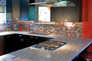 Example of a large trendy u-shaped ceramic tile open concept kitchen design in Albuquerque with a single-bowl sink, flat-panel cabinets, black cabinets, granite countertops, multicolored backsplash, glass tile backsplash, stainless steel appliances and a peninsula