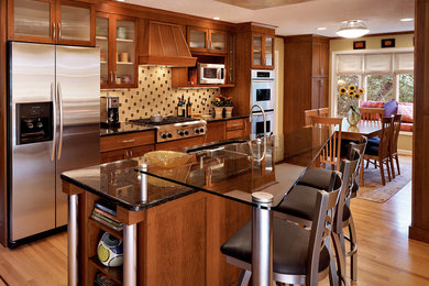 Eat-in kitchen - large transitional galley light wood floor eat-in kitchen idea in Bridgeport with glass-front cabinets, medium tone wood cabinets, multicolored backsplash, stainless steel appliances, a double-bowl sink, granite countertops, an island and black countertops