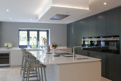 Foto på ett funkis kök med öppen planlösning, med släta luckor, grå skåp, bänkskiva i koppar, rostfria vitvaror och en köksö