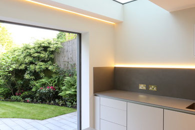This is an example of a contemporary kitchen in London with flat-panel cabinets and an island.