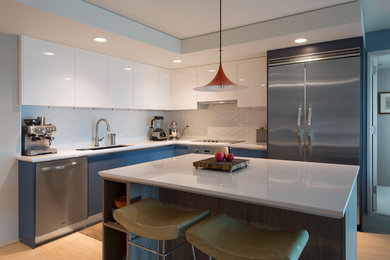 Medium sized contemporary l-shaped kitchen/diner in Hawaii with a submerged sink, flat-panel cabinets, blue cabinets, composite countertops, white splashback, stainless steel appliances, light hardwood flooring, an island, beige floors and white worktops.