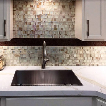 Contemporary kitchen with glass mosaic backsplash and gold calacatta counters