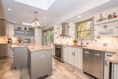 Large trendy l-shaped ceramic tile and beige floor eat-in kitchen photo in New York with a drop-in sink, flat-panel cabinets, beige cabinets, granite countertops, beige backsplash, stone tile backsplash, stainless steel appliances, an island and beige countertops