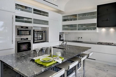 マイアミにある広いコンテンポラリースタイルのおしゃれなキッチン (アンダーカウンターシンク、フラットパネル扉のキャビネット、白いキャビネット、珪岩カウンター、パネルと同色の調理設備、セラミックタイルの床、白い床) の写真