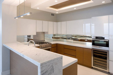 Example of a mid-sized trendy u-shaped concrete floor eat-in kitchen design in Chicago with an undermount sink, flat-panel cabinets, medium tone wood cabinets, marble countertops, metallic backsplash, mirror backsplash, stainless steel appliances and a peninsula