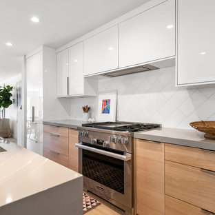 This is an example of a large contemporary l-shaped open plan kitchen in Los Angeles with an integrated sink, flat-panel cabinets, white cabinets, quartz benchtops, white splashback, marble splashback, stainless steel appliances, light hardwood floors, with island, beige floor and grey benchtop.