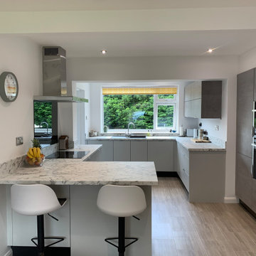 Contemporary light grey and concrete handleless kitchen with breakfast bar