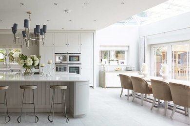 This is an example of a medium sized classic single-wall kitchen/diner in Other with a belfast sink, shaker cabinets, grey cabinets, marble worktops, marble splashback, integrated appliances, porcelain flooring, an island, grey floors and white worktops.
