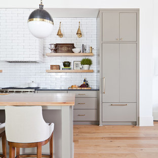Photo of a mid-sized contemporary single-wall open plan kitchen in Atlanta with an undermount sink, flat-panel cabinets, green cabinets, wood benchtops, white splashback, ceramic splashback, stainless steel appliances, light hardwood floors, with island and orange benchtop.