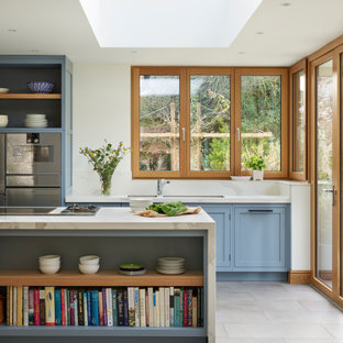 Inspiration for a large classic galley kitchen in Berkshire with a submerged sink, shaker cabinets, blue cabinets, stainless steel appliances, porcelain flooring, an island, grey floors and white worktops.