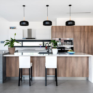 Design ideas for a contemporary kitchen in Perth with a drop-in sink, flat-panel cabinets, medium wood cabinets, black appliances, multiple islands, grey floor and white benchtop.