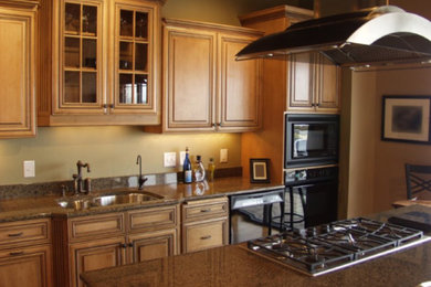 Foto de cocina comedor lineal contemporánea grande con armarios tipo vitrina, puertas de armario de madera clara, encimera de granito, salpicadero beige, una isla y encimeras marrones