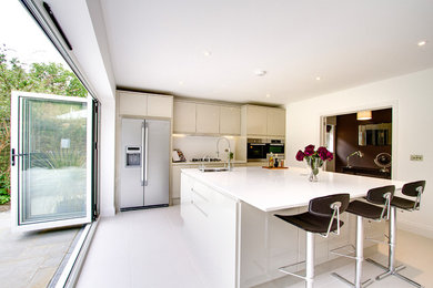 Medium sized contemporary single-wall open plan kitchen in Surrey with a built-in sink, flat-panel cabinets, grey cabinets, quartz worktops, white splashback, stainless steel appliances, ceramic flooring, an island and white floors.