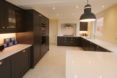 Design ideas for a large contemporary u-shaped kitchen/diner in Surrey with an integrated sink, shaker cabinets, black cabinets, quartz worktops, grey splashback, porcelain splashback, integrated appliances, porcelain flooring and a breakfast bar.