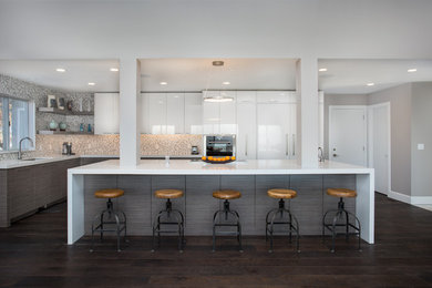 Example of a large trendy l-shaped dark wood floor and brown floor eat-in kitchen design in Salt Lake City with an undermount sink, flat-panel cabinets, beige backsplash, mosaic tile backsplash, stainless steel appliances, an island, white cabinets and quartzite countertops